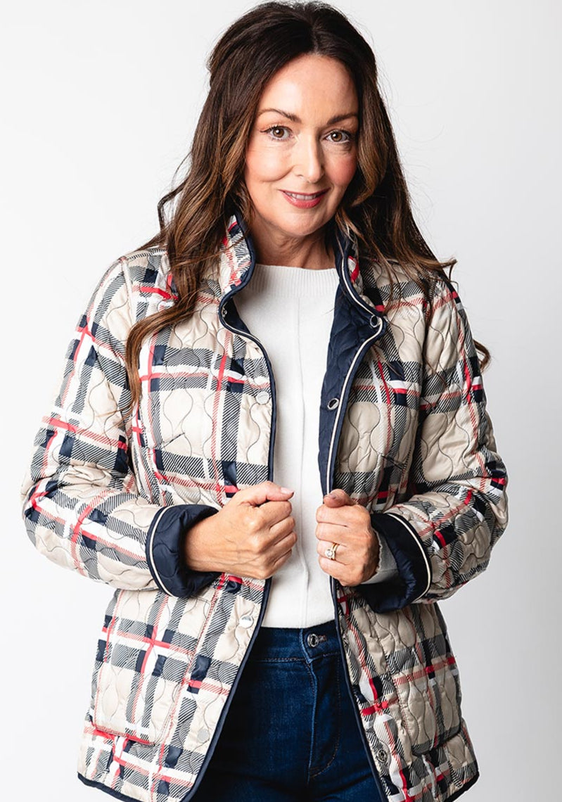 Woman wearing a plaid jacket over a white shirt and blue jeans on a white background