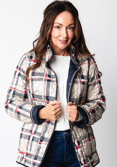 Woman wearing a plaid jacket over a white shirt and blue jeans on a white background